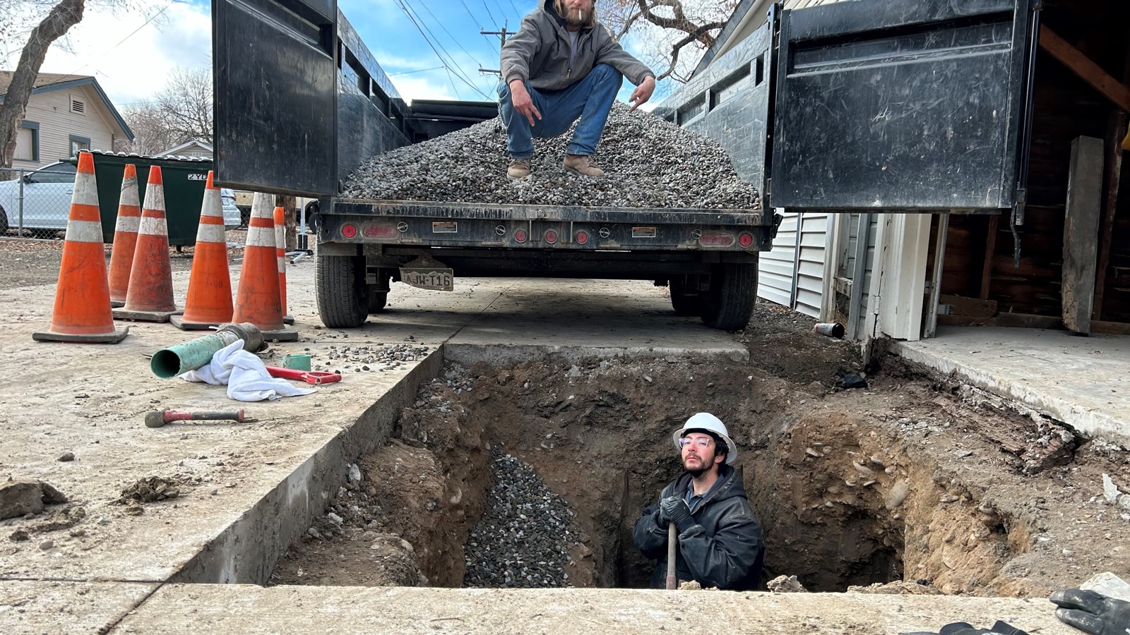 Workers excavating and rebuilding a residential sewer-line connection